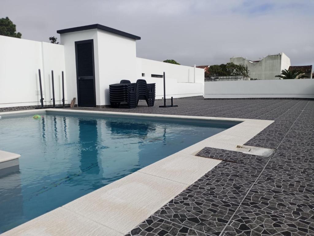 a swimming pool with two chairs next to a building at The Rock Hostel in Ponta Delgada