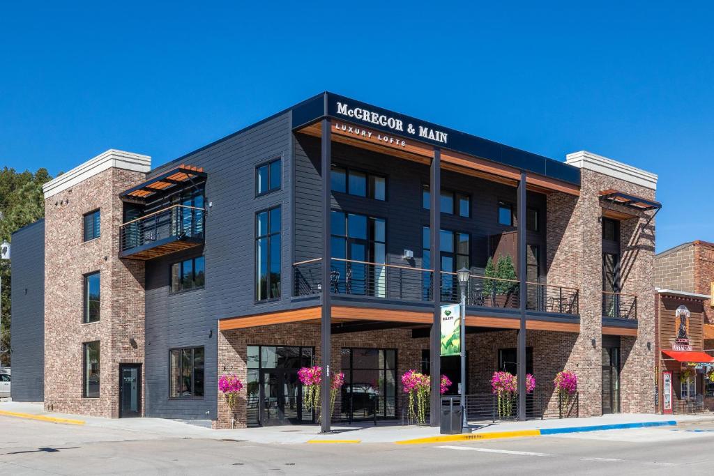 a building on a street with pink flowers at McGregor & Main - Luxury Lofts in Hill City