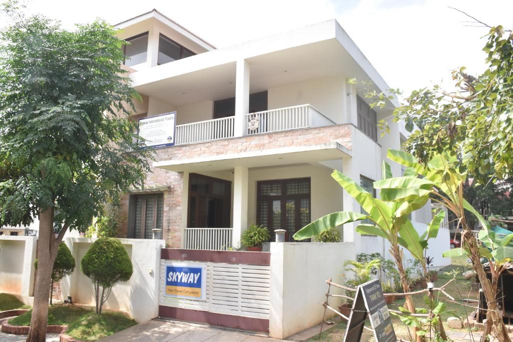 a white house with a tree in front of it at MAHAMAYA HOME STAY in Mysore