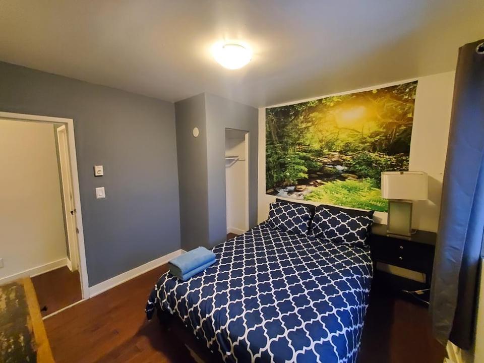 een slaapkamer met een blauw bed en een schilderij aan de muur bij 375$/Week // Room B // Full Kitchen in Montreal