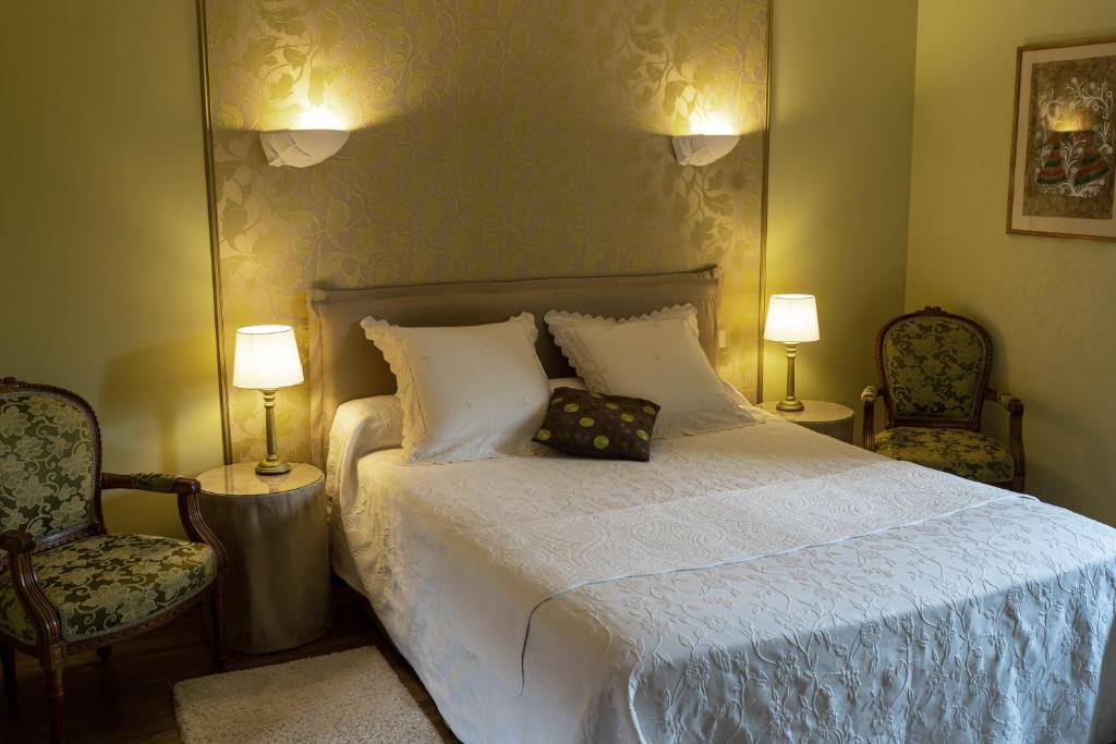 a bedroom with a bed with two chairs and two lamps at Château de Ribourdin in Chevannes