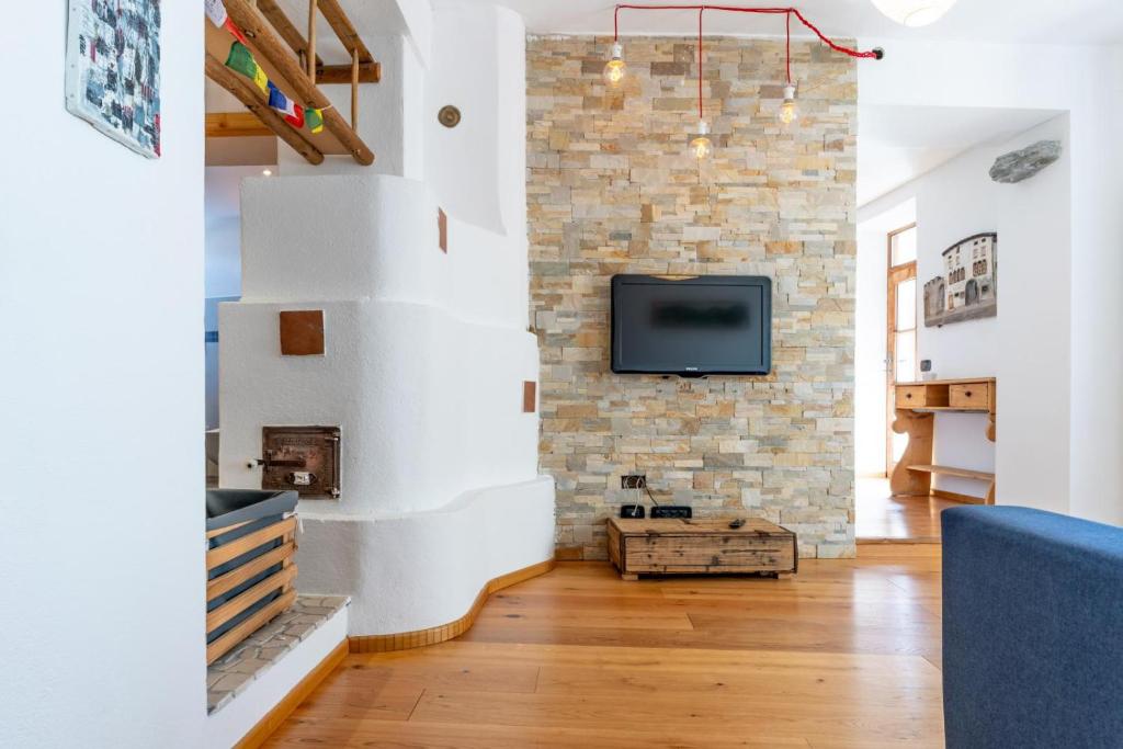 a living room with a brick wall and a tv at Alla Contrada, Pergine Valsugana Ospitar in Pergine Valsugana