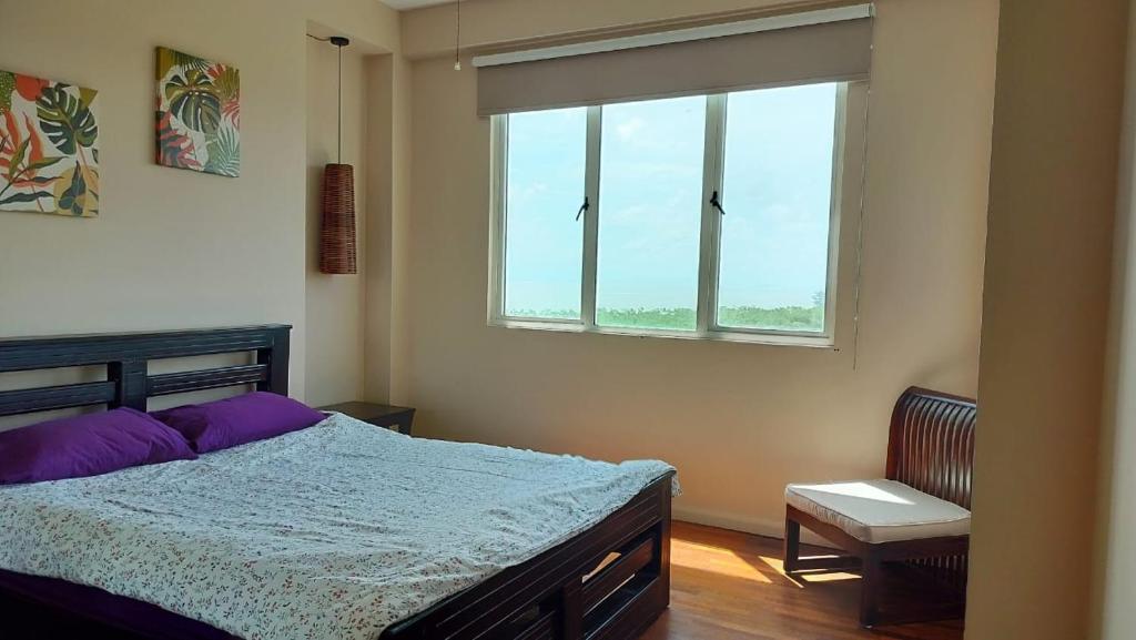 um quarto com uma cama grande e uma janela em The Apartment at Santubong em Kuching