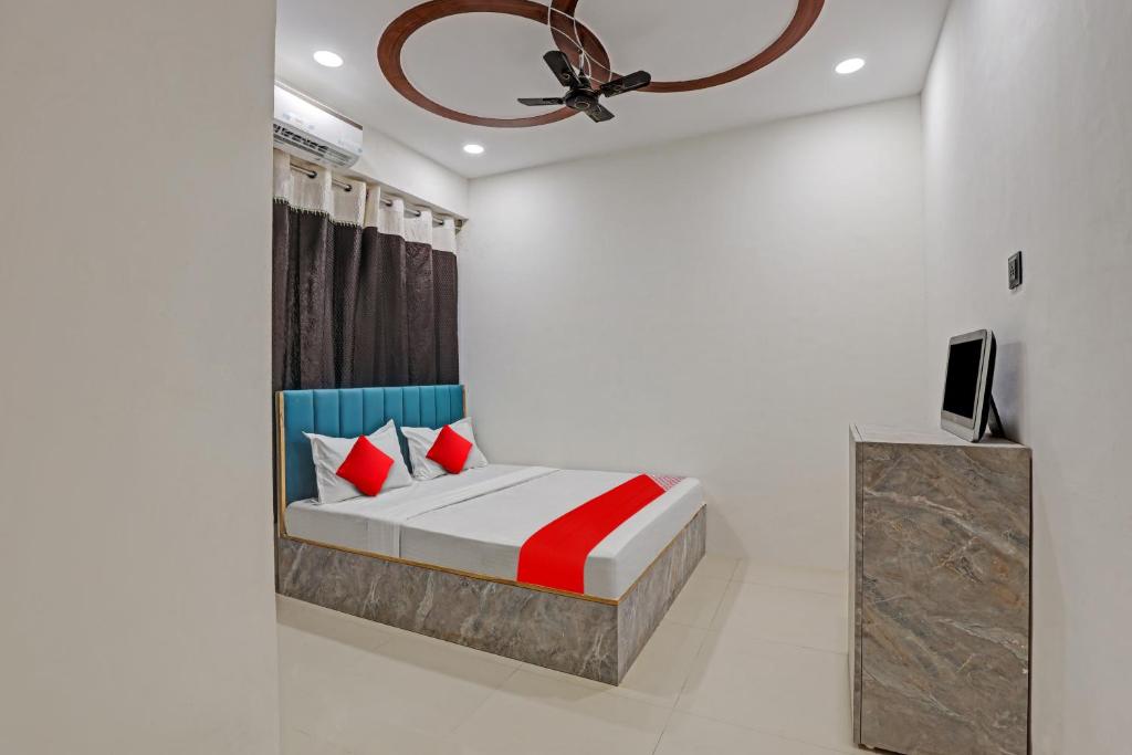 a bedroom with a bed with red pillows and a ceiling fan at Vr Hotel in Surat