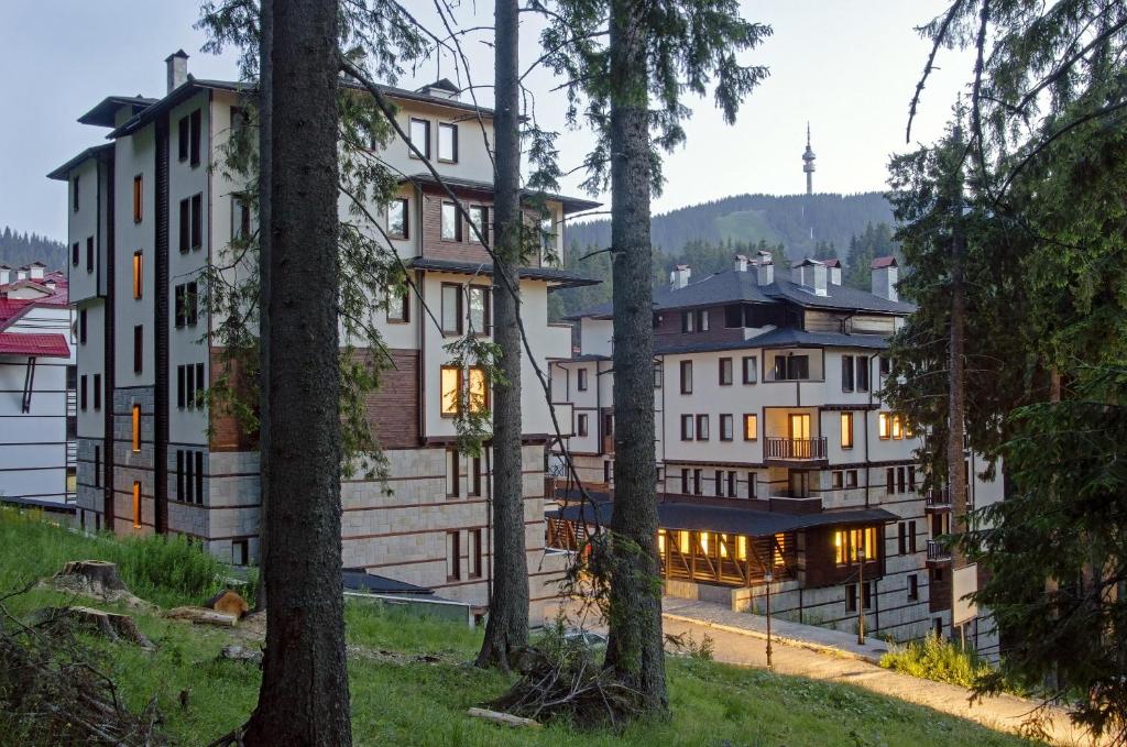 a group of buildings in a forest with trees at Green Life Family Apartments Pamporovo in Pamporovo