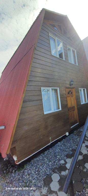 ein Haus mit einem roten Dach mit einer Tür in der Unterkunft Fortunata del Beagle in Puerto Williams
