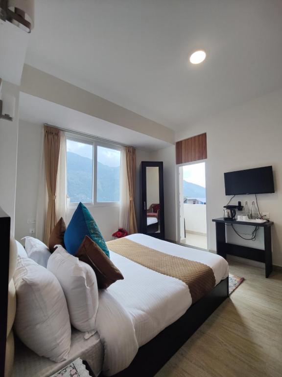 a bedroom with a large bed with pillows and a television at Maplewood Hotel & Spa in Gangtok