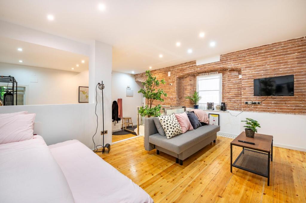a living room with a couch and a brick wall at Maravilloso apartamento centro de Madrid Malasaña in Madrid