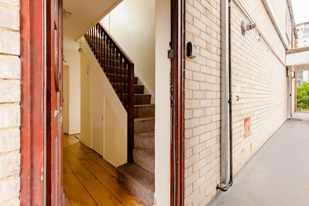 an empty hallway with stairs and a brick wall at Cosy Room by Canary Wharf in London