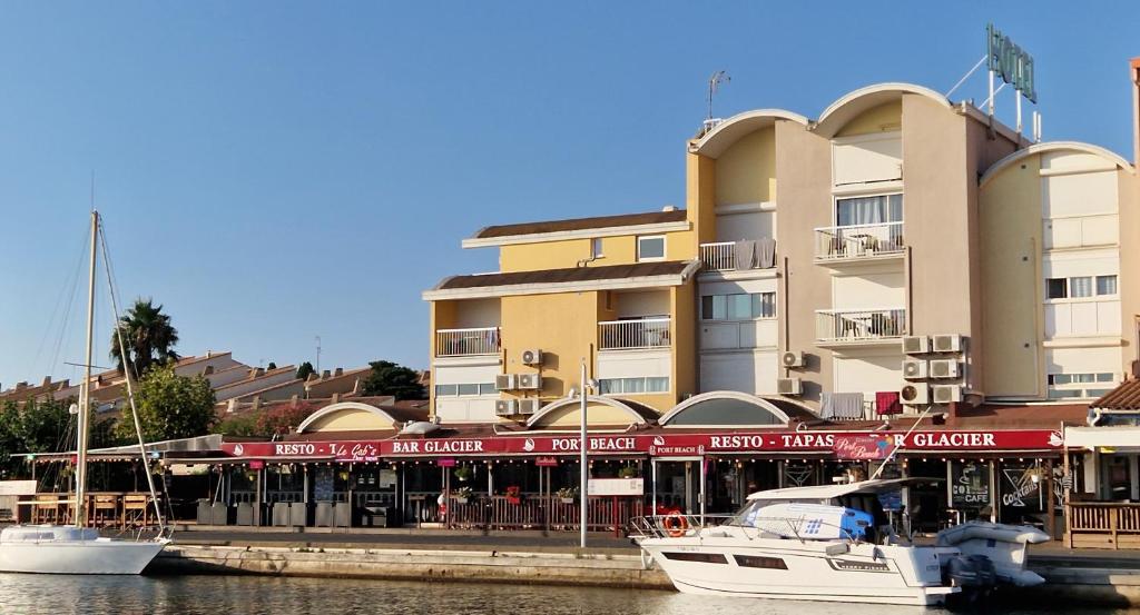 dos barcos están atracados frente a un edificio en Hôtel Port Beach, en Gruissan