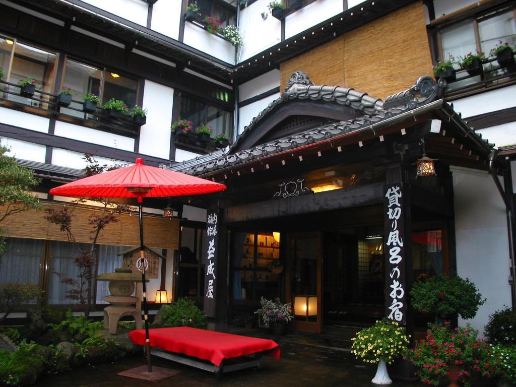 a red umbrella and a bench in front of a building at Ekinariya Ryokan in Kusatsu