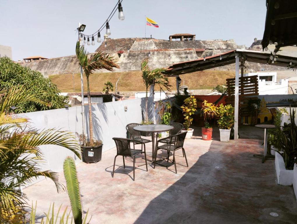un patio con mesa, sillas y palmeras en Del Castillo Mirador Hostel, en Cartagena de Indias