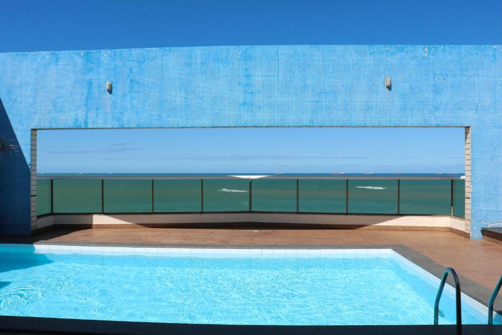 a swimming pool in a building with a large window at Flat reformado 1306 na Praia da Costa 1950 Edifício Ocean Flat in Vila Velha