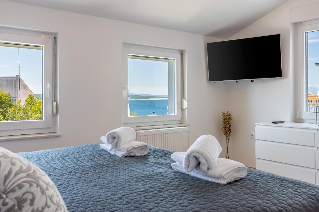 a bedroom with a bed with towels and a flat screen tv at Penthouse apartment Victoria in Crikvenica