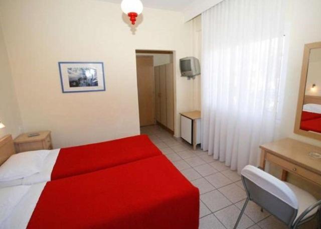 a hotel room with a red bed and a desk at Hanioti hotel in Hanioti