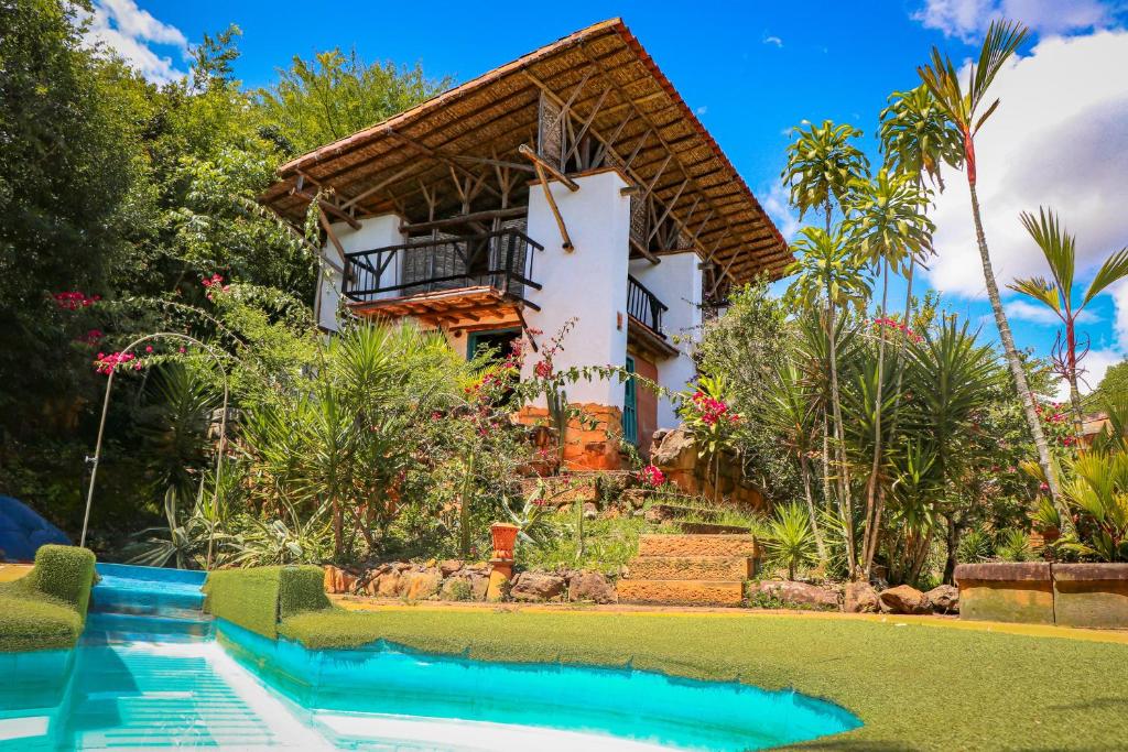 a villa with a swimming pool in front of a house at Hotel El Cogollo By MH in Barichara