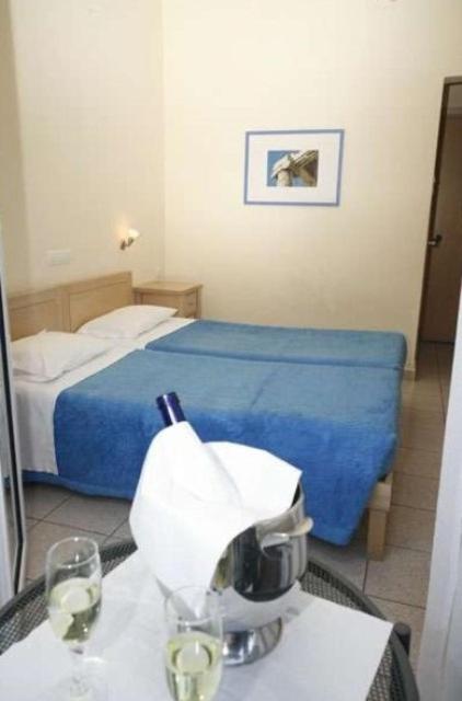 a hotel room with a bed and two glasses of wine at Hanioti hotel in Hanioti