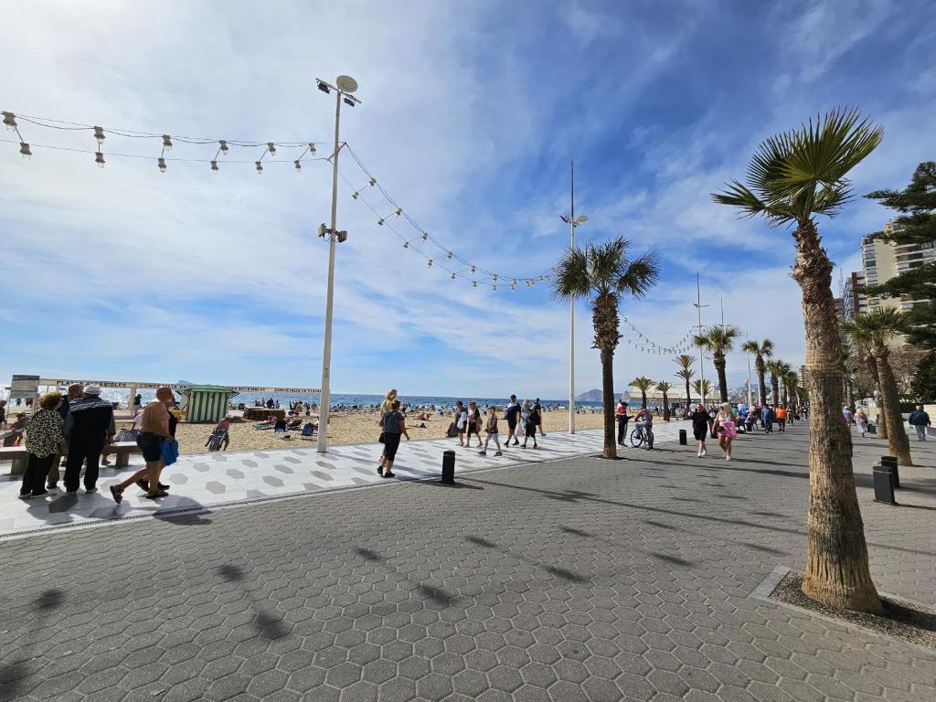 eine Gruppe von Menschen, die auf einem Bürgersteig in Strandnähe spazieren in der Unterkunft Apartamento Bacana Beach in Benidorm