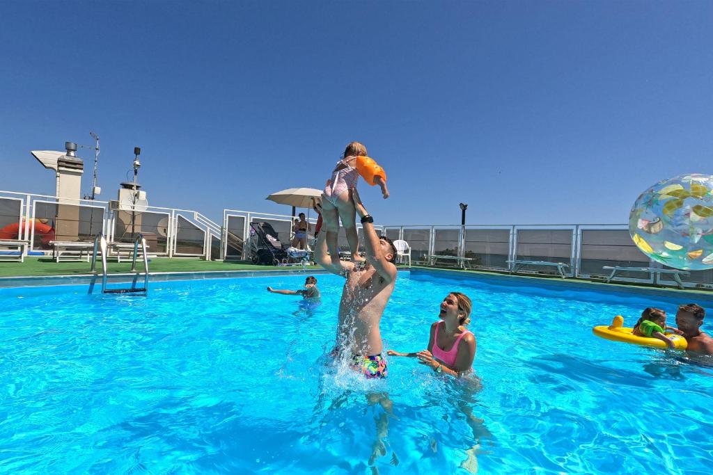 een man die een kind vasthoudt in een zwembad bij Hotel Sorriso in Lido di Classe