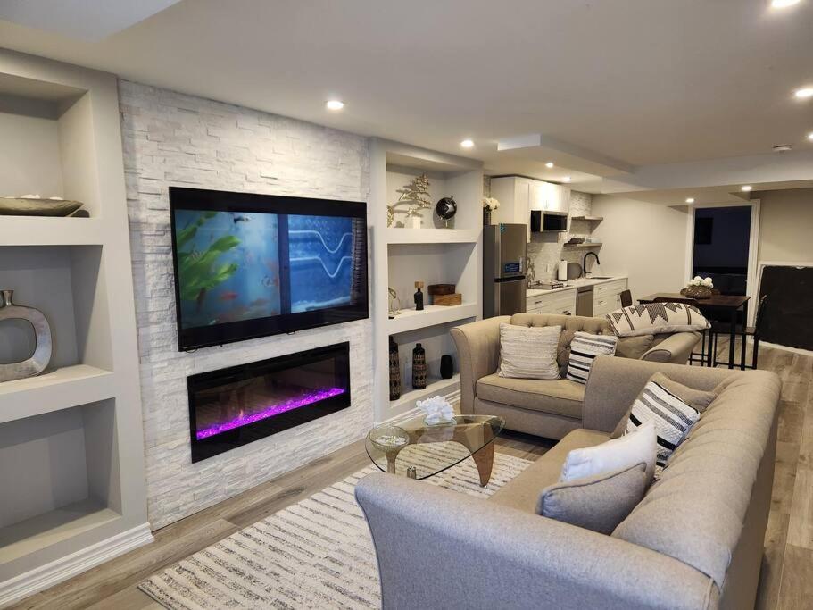 een woonkamer met een tv aan een bakstenen muur bij Stylish Retreat in North Oshawa in Oshawa