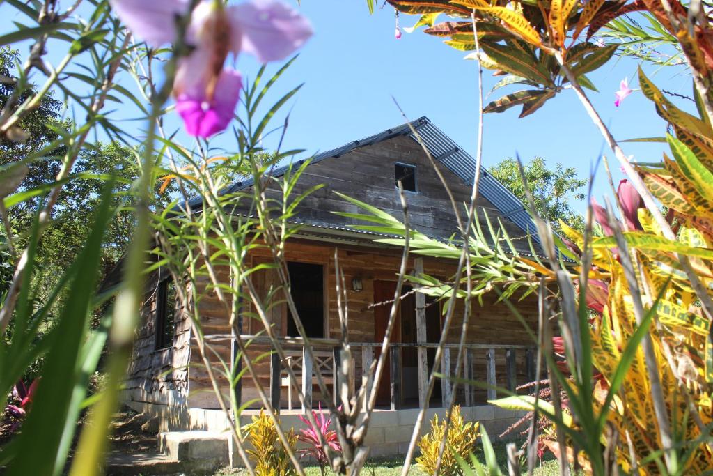 een houten huis met bloemen ervoor bij Rancho Los Duendes in Turrialba