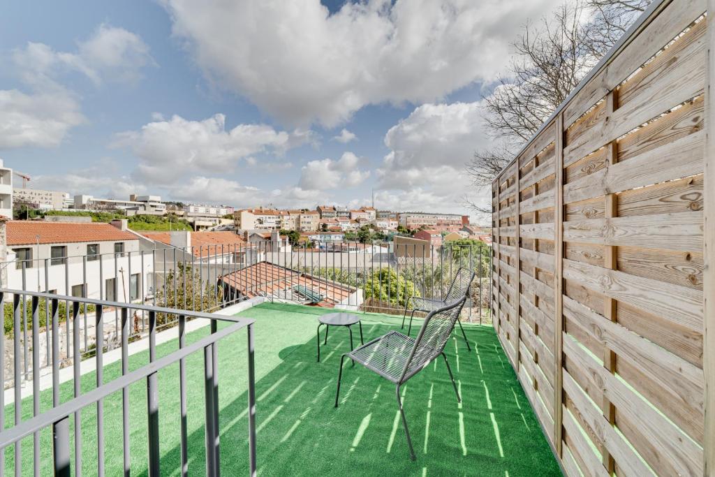a balcony with a green floor and two chairs at By the Palace - Ajuda Apartments in Lisbon