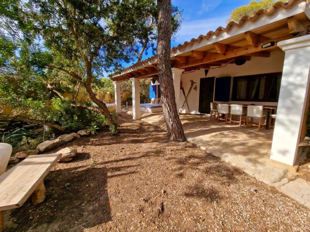 an outdoor patio with a bench and a tree at Casa Migjorn, immersa nella natura a pochi passi dal mare in Es Calo