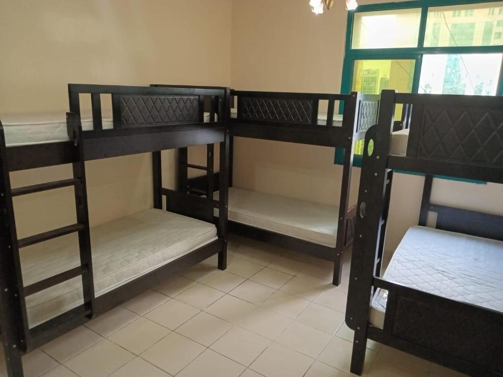 three bunk beds in a room with a window at SHARING BED SPACE FOR MALE near DUBAI BUS STOP in Sharjah