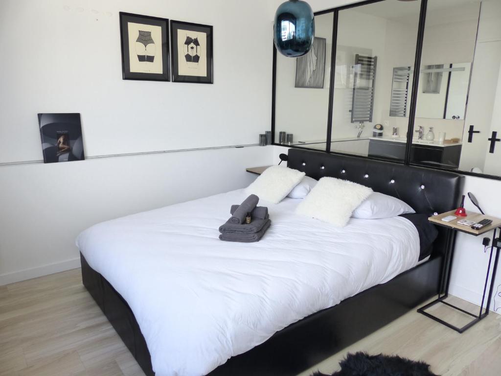 - un lit avec une tête de lit noire et des oreillers blancs dans l'établissement La Cité des Coeurs LU Parking inclus, à Nantes