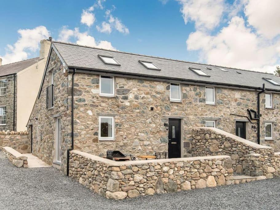 a stone house with a stone wall at Pipistrelle Cottage a quirky gem near Snowdonia in Caernarfon