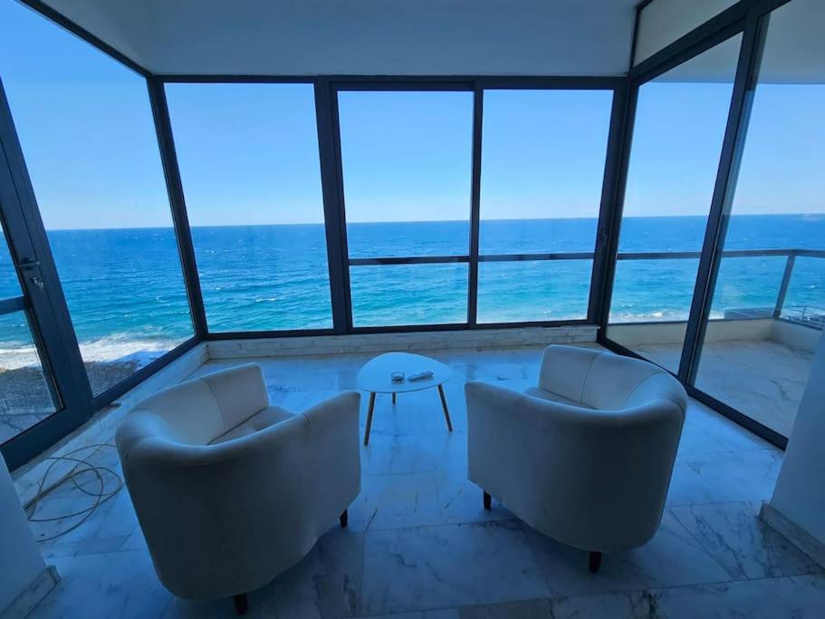 a room with two chairs and a table and the ocean at XL Seafront Home in Sliema in Sliema