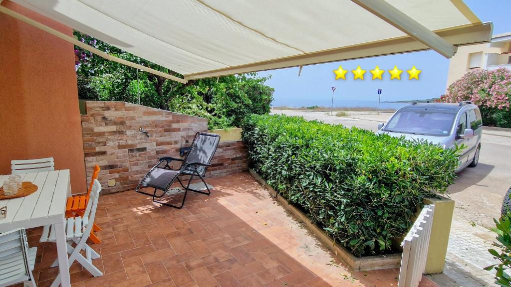 a patio with a table and chairs under a white umbrella at Rifugio costiero in Fertilia