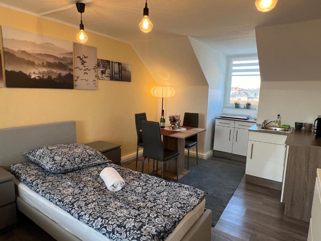 a bedroom with a bed and a table and a kitchen at Studio Apartment Frühauf Geithain in Geithain
