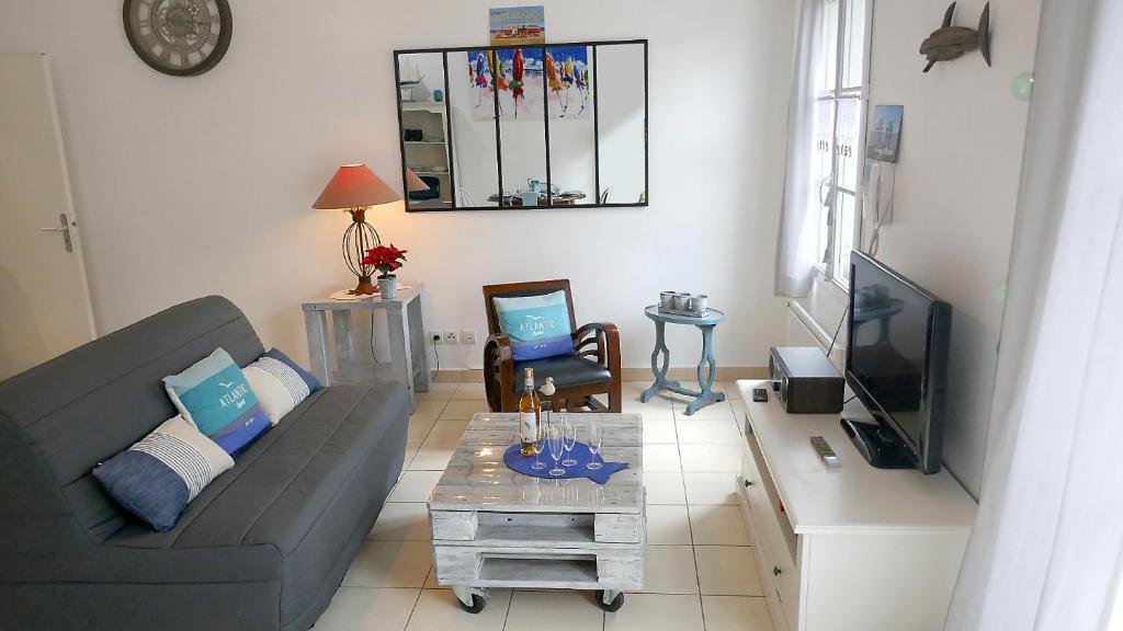 un salon avec un canapé et une télévision dans l'établissement Maison PASSIFLORE, à Saint-Denis-dʼOléron