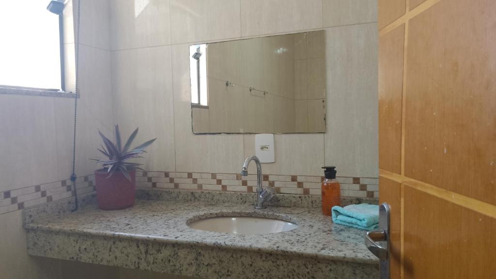 a bathroom with a sink and a mirror at Suíte próxima à Univas/Fátima in Pouso Alegre