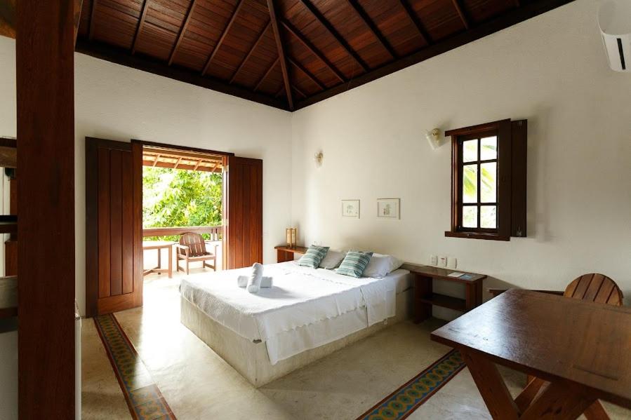 1 dormitorio con cama, mesa y ventana en Pousada Vila do Beco, en Arraial d'Ajuda