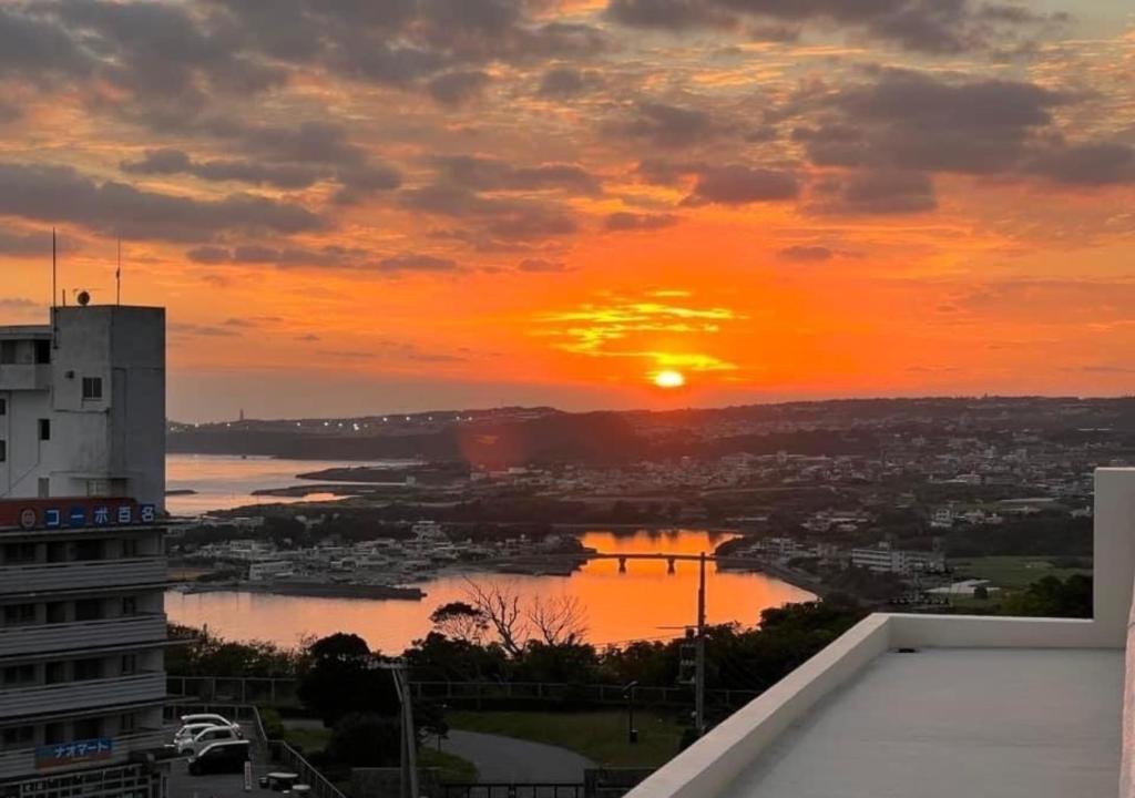 Blick auf den Sonnenuntergang über einer Stadt und einem Fluss in der Unterkunft Condominium Hotel Okinawa Yumeto - Vacation STAY 16527v in Nanjō