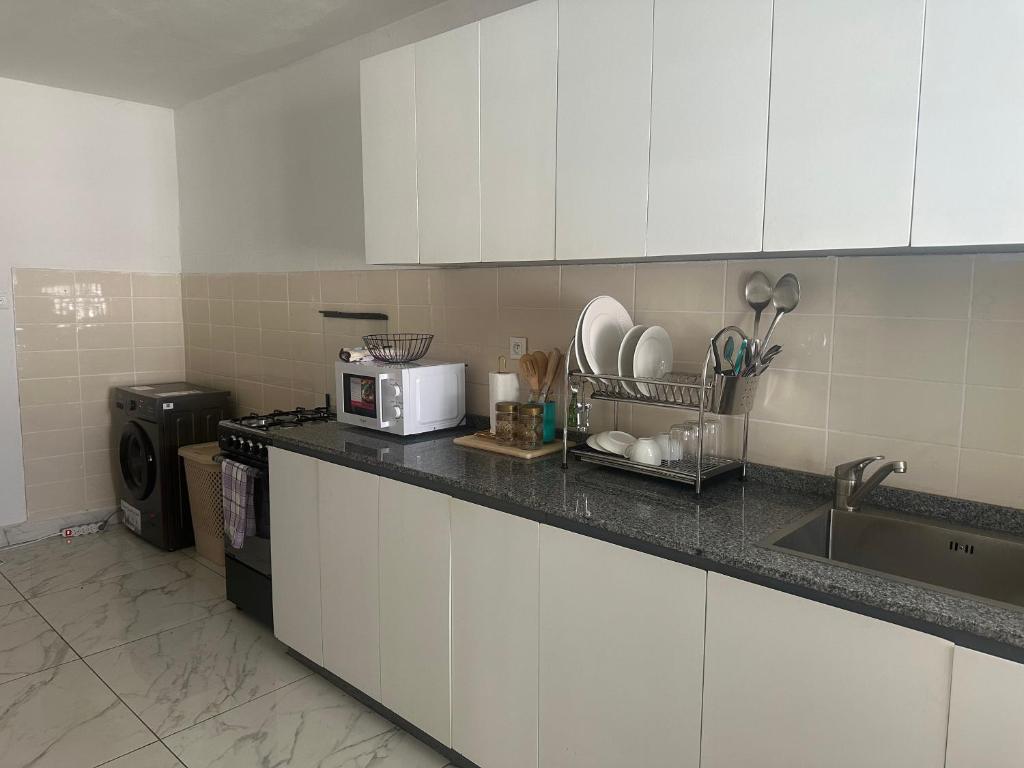 a kitchen with white cabinets and a sink and a microwave at Villa ocean bord de mer louis in Libreville