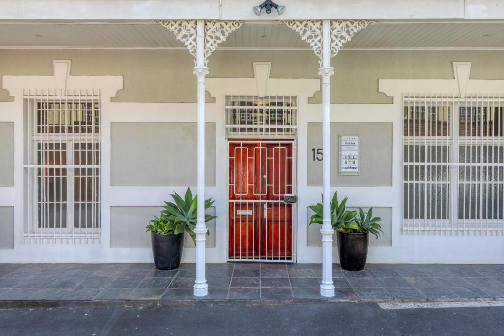 a red door on a building with two potted plants at Modern victorian city house, work, live, play! in Cape Town