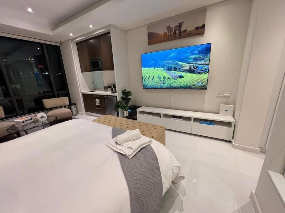 a bedroom with a large bed and a tv on the wall at NEW Luxury Hotel Suite Sandton City in Johannesburg