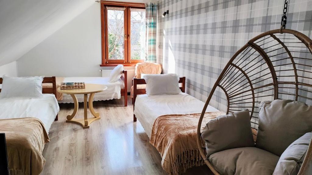 um quarto com duas camas e uma cadeira e uma mesa em Apartament Pod Lipami em Suwałki