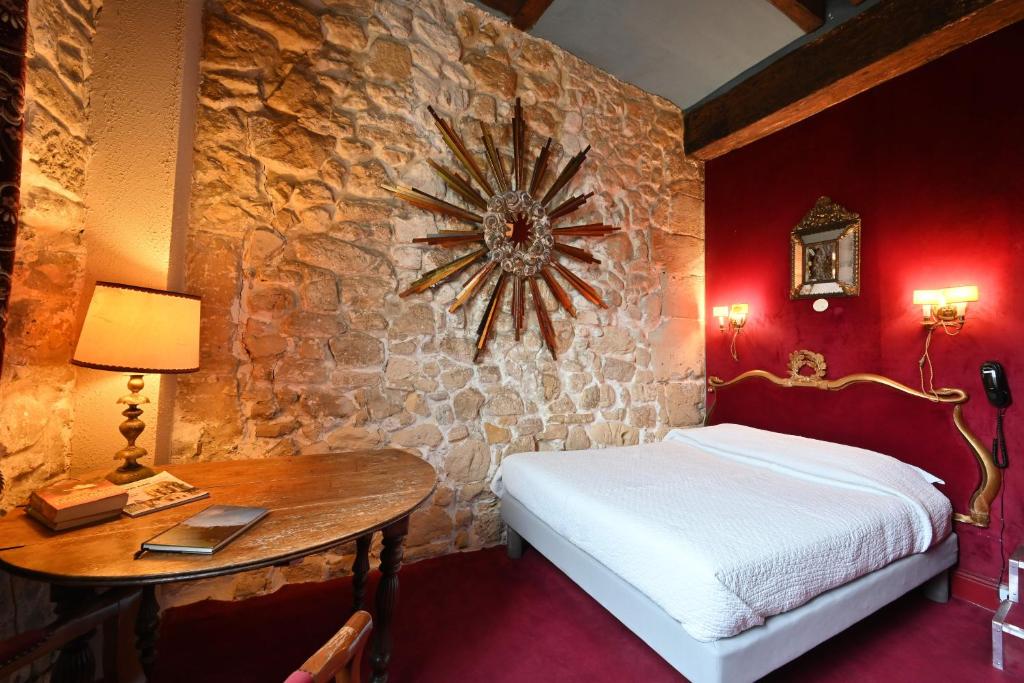 a bedroom with a bed and a table with a clock on the wall at Hotel Esmeralda in Paris
