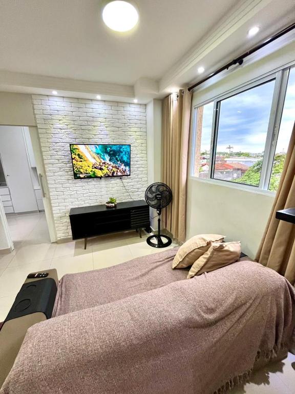 a bedroom with a large bed and a large window at Ohanacaiçara apartamento próximo à praia do Sesc, completo e com Wi-Fi. in Bertioga