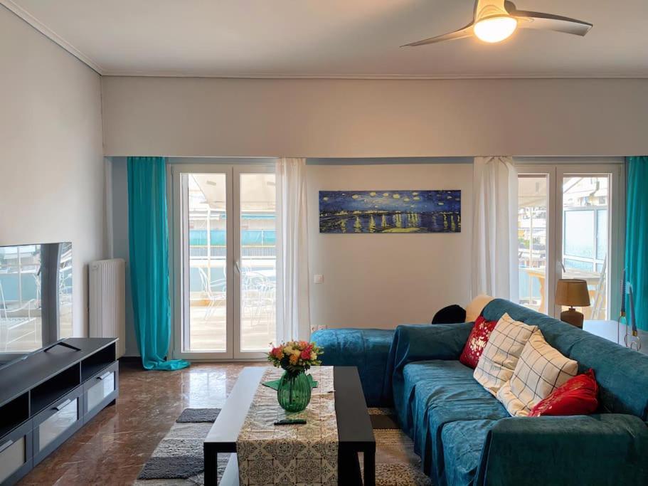 un soggiorno con divano blu e tavolo di Glorious Mediterranean 顶层海景公寓 ad Atene