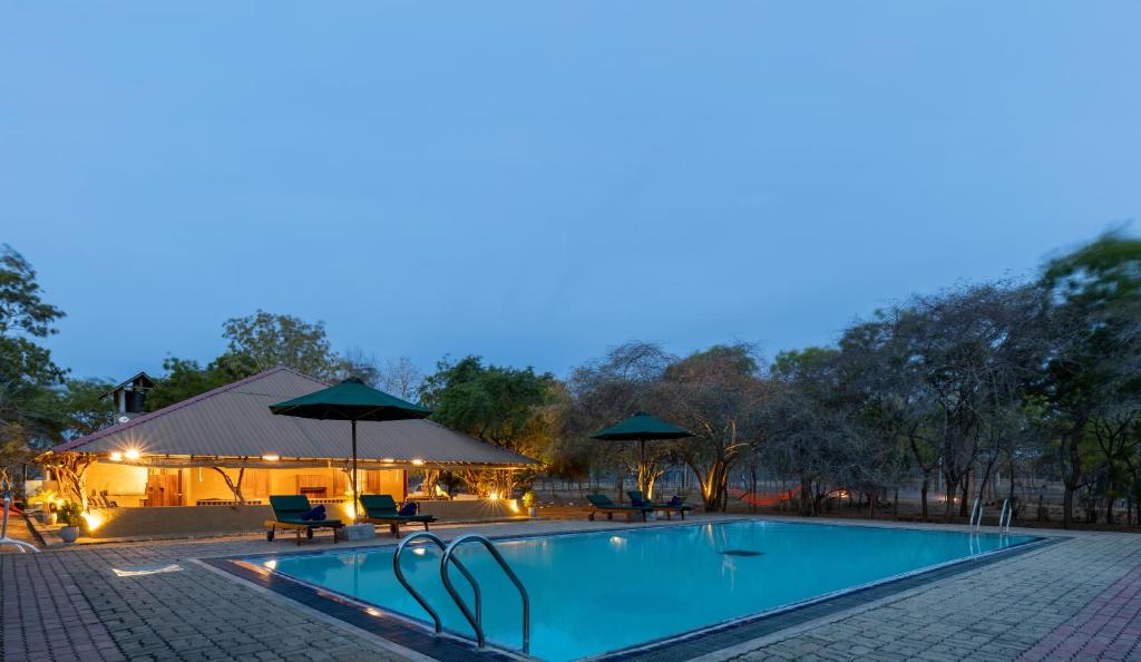 a pool with chairs and umbrellas next to a building at Joe's Bungalow Yala in Kirinda