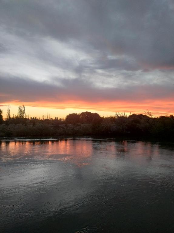 Blick auf einen Fluss mit Sonnenuntergang im Hintergrund in der Unterkunft Soler in Rawson