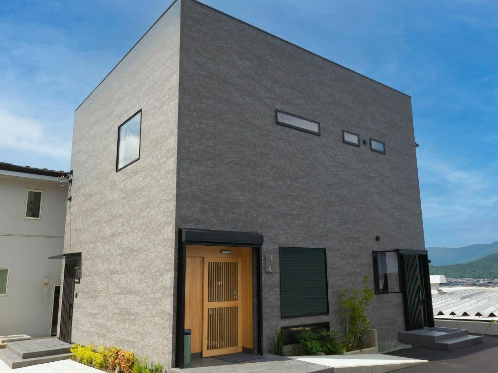 ein graues Backsteinhaus mit einer Holztür in der Unterkunft SWEET VILLA TAKASAMA2 - Vacation STAY 11608v in Fujiyoshida