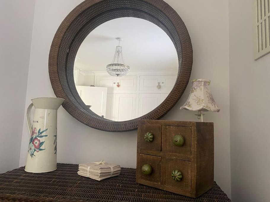 a mirror on a wall above a table with a vase at Cosy cottage in Chard