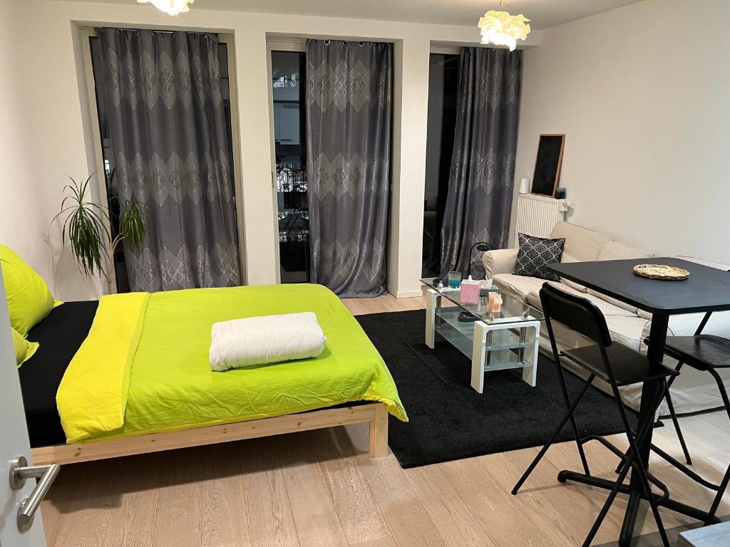 ein Wohnzimmer mit einem grünen Bett und einem Tisch in der Unterkunft Belle appartement commission européenne in Brüssel