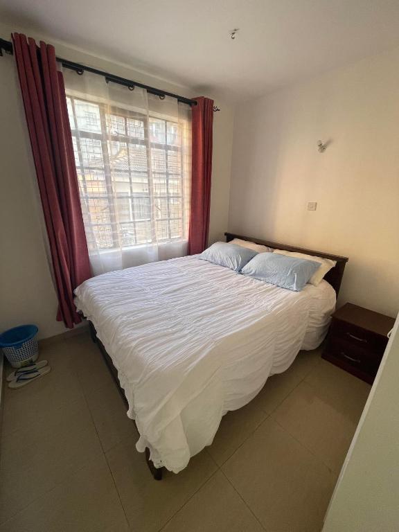 a bedroom with a large white bed with a window at Langata, Deliverance Church, Jamhuri Heights Apartments in Nairobi